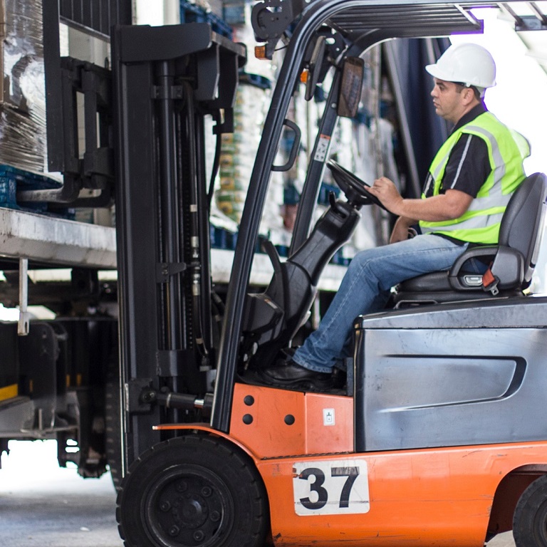 A forklift loads goods onto a truck in a warehouse, illustrating the risks of underinsurance during transit.