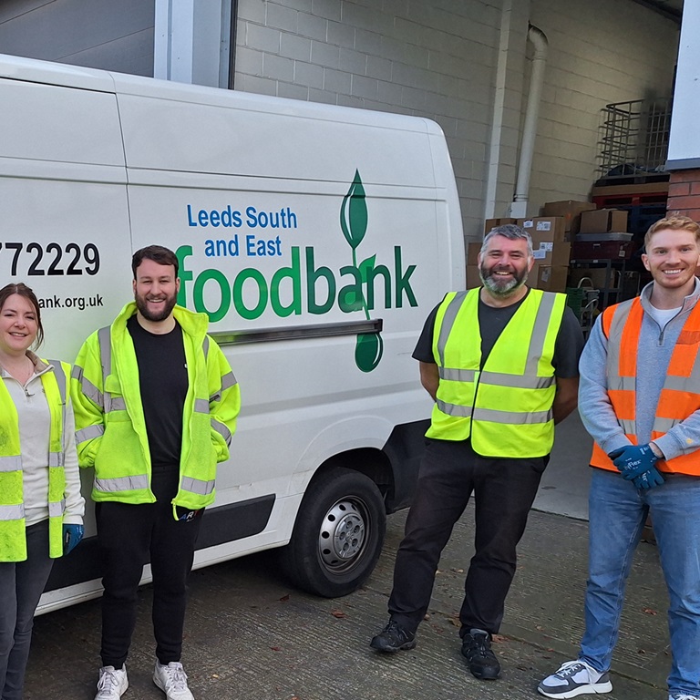 Marsh Commercial colleagues standing and smiling in front of a Leeds South and East Foodbank van